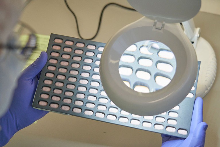 A lab technician visually inspects COVID-19 Paxlovid tablet samples in Freiburg, Germany.