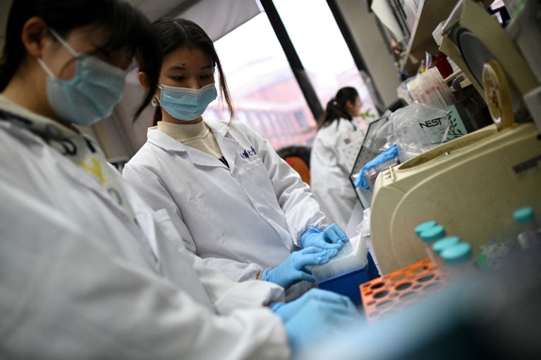 Low-angle view of two female laboratory technicians wearing face coverings and white lab coats