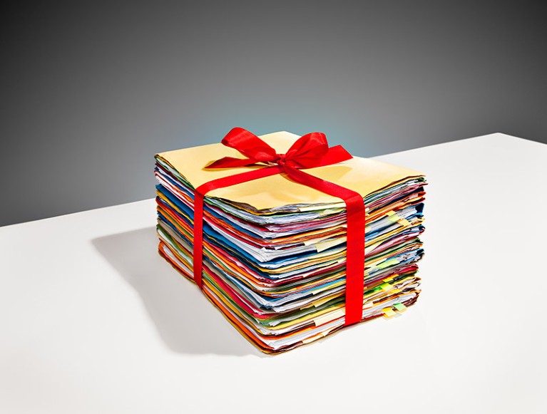 Large stack of files on a tabletop, wrapped with a red bow