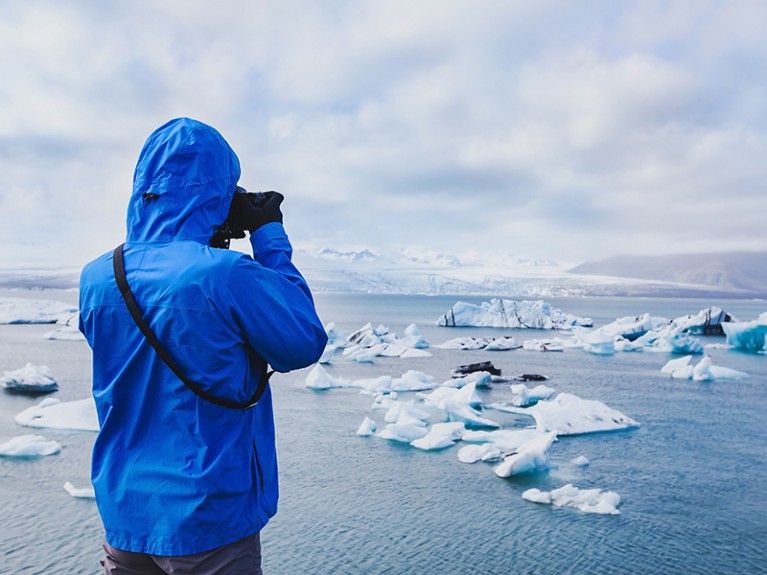 Person takes photo of arctic icebergs in Iceland.