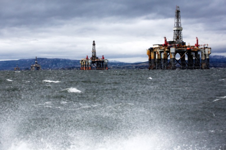Unused oil rigs are seen from a boat in the Port of Cromarty Firth on a dark and cloudy day