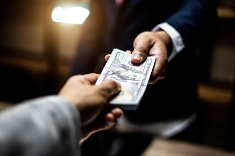 Close-up of one hundred dollar bills being passed between two people