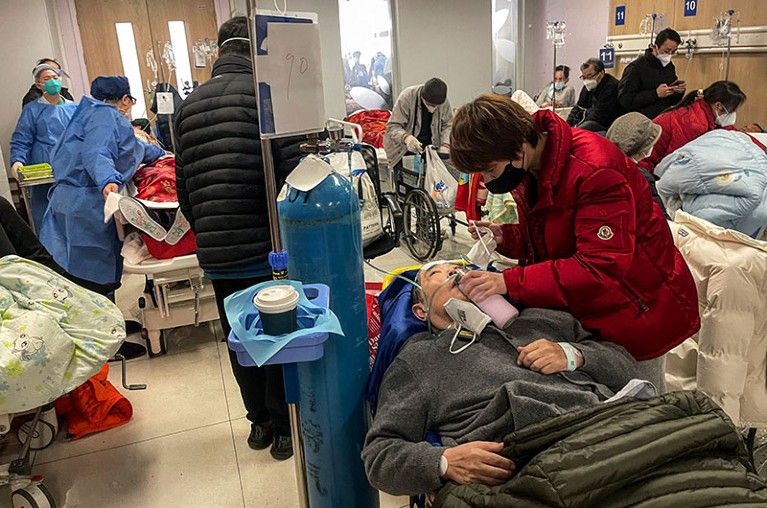 A woman helps a patient in a crowded hospital in Shanghai.