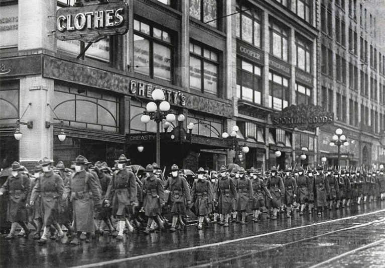 Black and white archive image of US soldiers of the 39th Regiment marching in Seattle wearing face masks