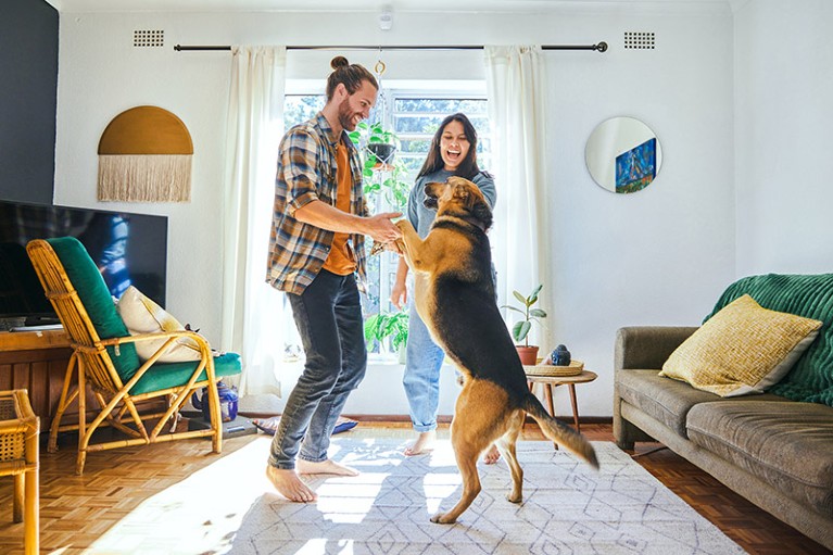 young couple dancing with their pet dog in living room