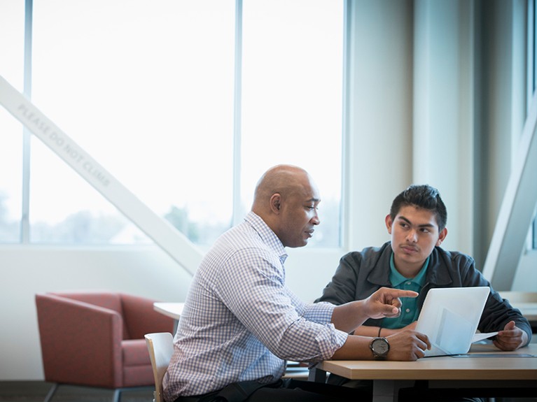 Mentor helping student use laptop.