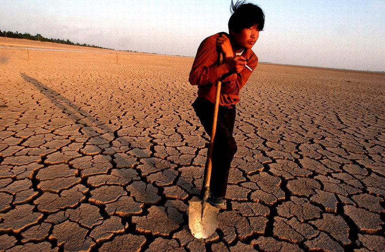 A Worker Takes a Rest On the Chapped Land in a Dried Reservior in Minqin in Northwest China's Gansu Province