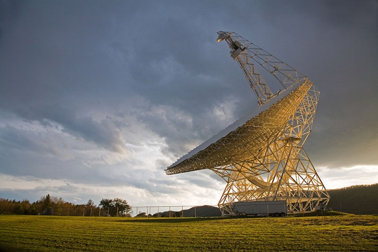 A radio telescope against a cloudy sky.