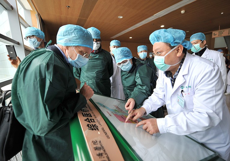 World Health Organization representatives speak with scientists at a Wuhan medical facility in February 2020