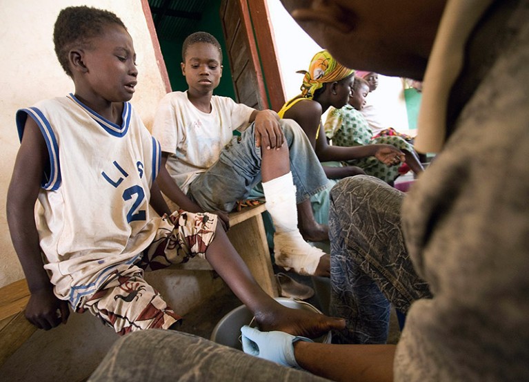 A boy cries as a health worker extracts a guinea worm from his ankle.