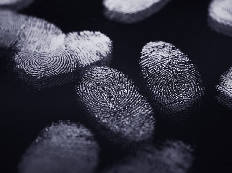 Multiple fingerprints in white on a dark surface.