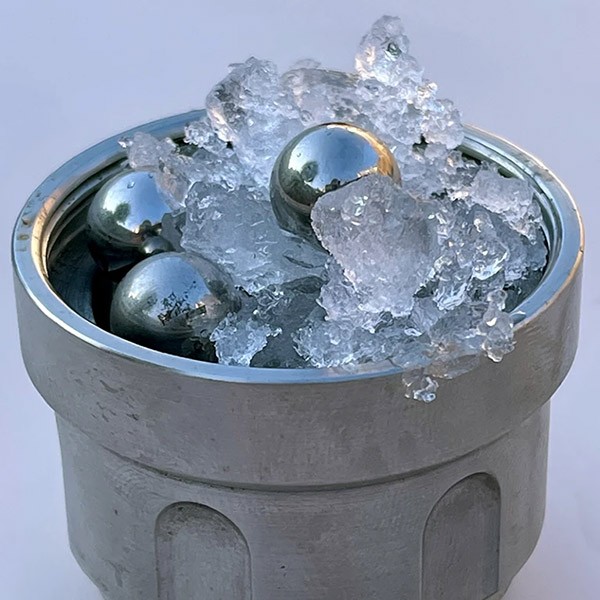 A closeup photo of a round metal container filled with what looks like crushed ice and three shiny metal balls.