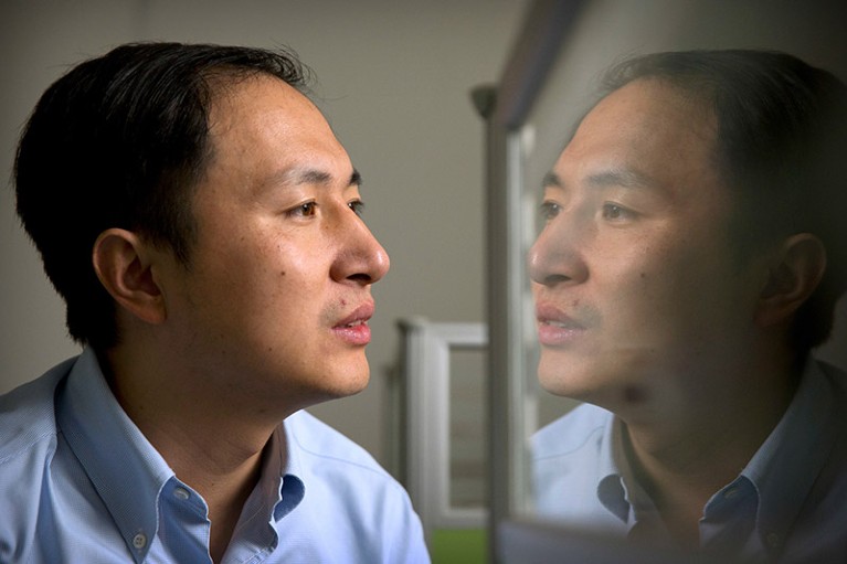 He Jiankui is reflected in a glass panel as he works at a computer at a laboratory in Shenzhen, China