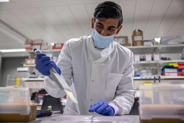 Rishi Sunak in a laboratory at the National Institute for Health Research wearing a white lab coat and face mask