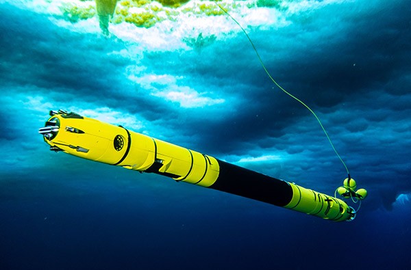 The Icefin robot, a long, thin yellow cylinder, is exploring the waters directly underneath the ice layer in Antarctica.