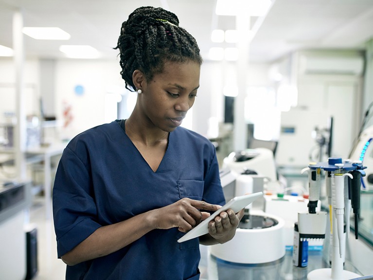 20多岁的黑人女性病理技术员在实验室使用数字平板电脑的正面特写。
