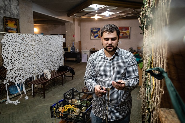 Ivan Brusak, a graduate student and member of Lviv Polytechnic’s Student Volunteers, weaves a camouflage net, in Lviv, Ukraine.