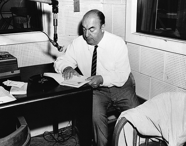 Pablo Neruda reads from his poetry while in front of a microphone, during a radio interview.