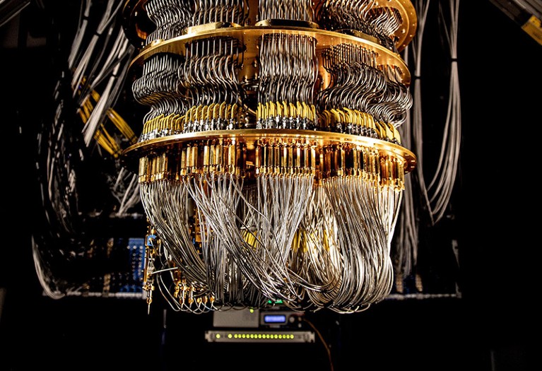 The base of Google Quantum AI computer showing shiny silver wires and gold connectors linking the bottom to top of device