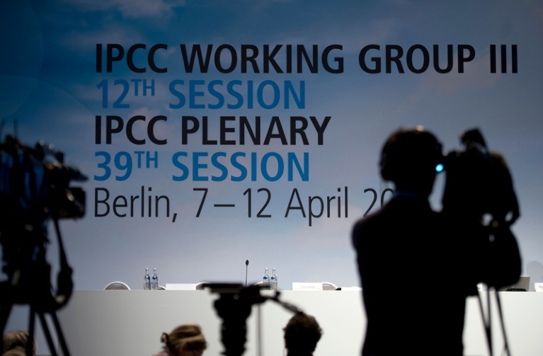 A silhouette of media representatives stand in front of the IPCC Working Group III's conference