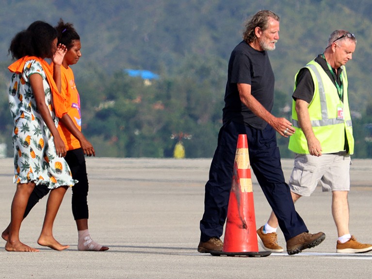 Four people cross the tarmac at an airport.