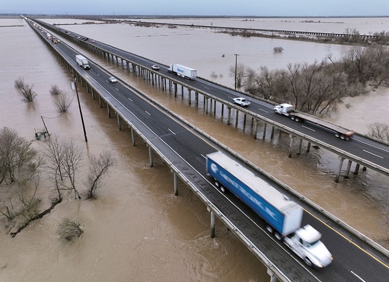 Vehicles drive on Interstate 5 over the rainwater-flooded Yolo Bypass in Woodland, California.