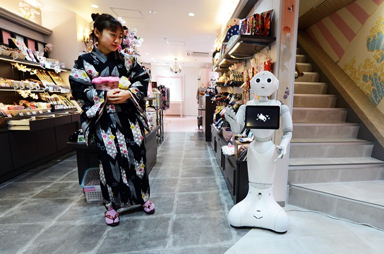 A woman dressed in Kimono interacting with a robot