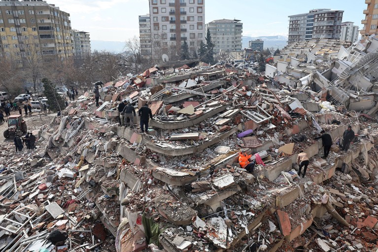 Civilians look for survivors under the rubble of a multi-storey collapsed buildings