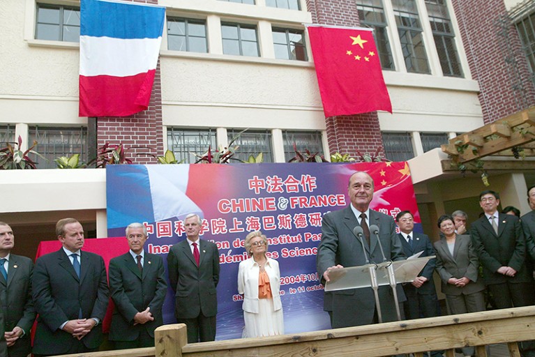 Jacques Chirac and other dignatories in front of a sign in French and Chinese, and French and Chinese flags.