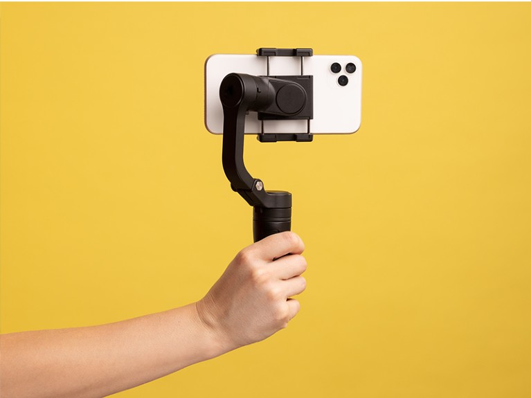 Closeup side view of woman hand holding steadicam with phone, for making video or has livestream.