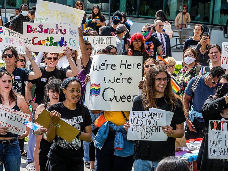 A group of Florida International University students, staff and community members hold placards in a protest.