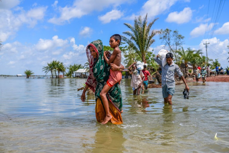 人们被淹没的公路交叉Satkhira Amphan飓风登陆后,孟加拉国。