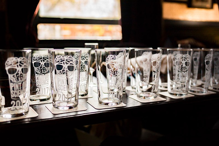 Empty Pint of Science branded pint glasses from 2017 laid out on a table with diffuse background.