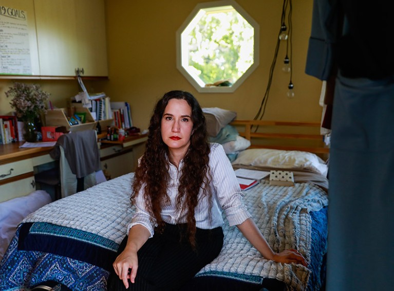 Jaime Seltzer poses for a portrait in her room sat on the edge of her bed.