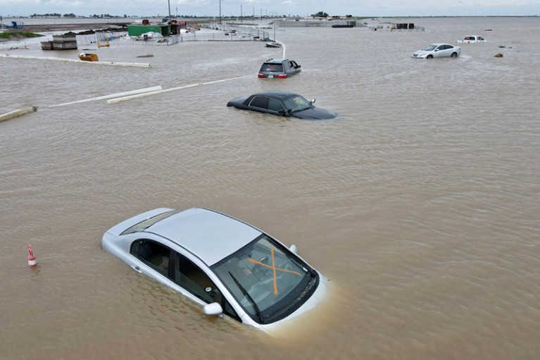 Cars partially submerged in brown floodwater.