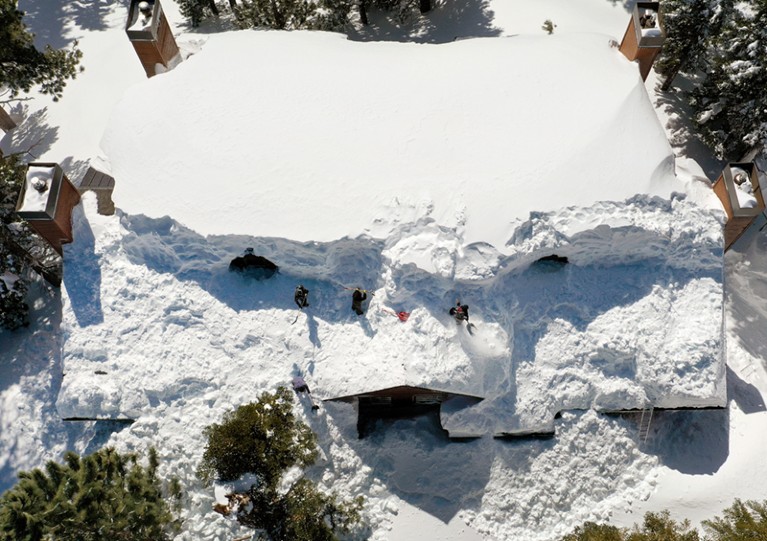 在加州猛犸湖的内华达山脉，工人们正在清除屋顶上的积雪。