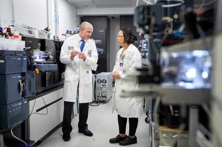 Randall Bateman talks with a colleague in a lab