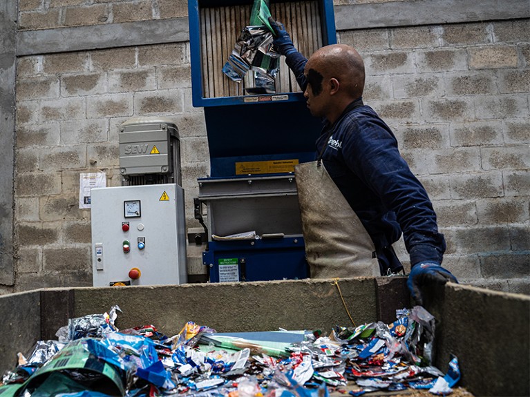A worker feeds plastic waste into a crushing machine at the IngePol reuse and recycling facility in Medellin, Colombia.