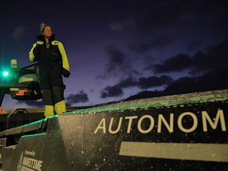 Emily Venables stands atop Unmanned Surface Vehicle (USV) called Apherusa.