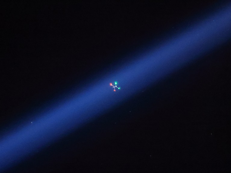 Searchlight frames hovering quadcopter as it photographs illumination footprint of R/V Helmer Hanssen