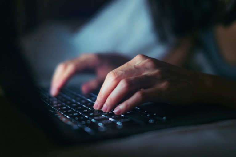 一个女人晚上在笔记本电脑上打字的手特写