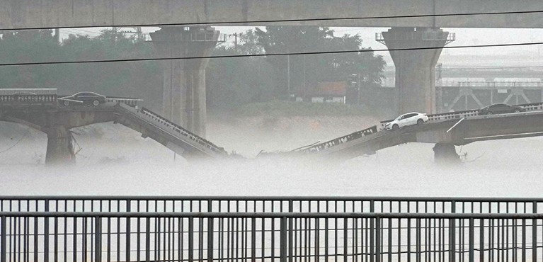 Collapsed bridge with vehicles left abandoned on it.