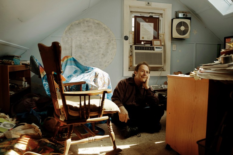 Rick Doblin sits cross-legged, with his head in his left hand, on the floor in his home