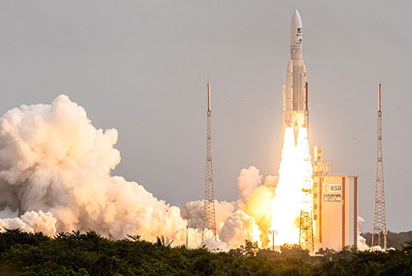 Arianespace's Ariane 5 rocket lifting off from its launchpad with exhaust flames and billowing smoke.