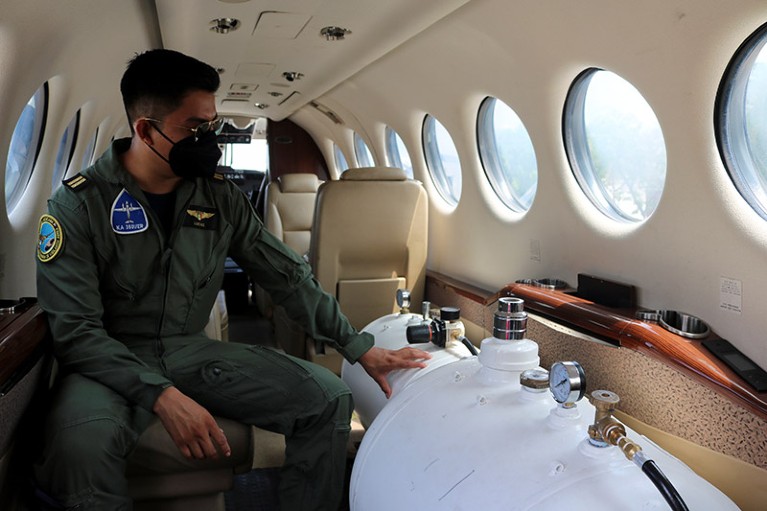 A member of the Air Force sit next to the tanks with cloud seeding solution in a King Air 350i plane.