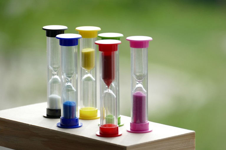 Six small coloured sand timers on a wooden box