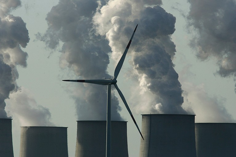 A wind turbine stands in front of plumes coming from cooling towers at the Jaenschwalde power station in Germany.