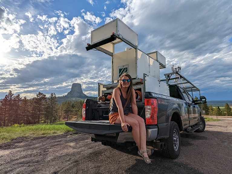 Elizabeth sits on the back of a truck that carries a Doppler lidar and other equipment.