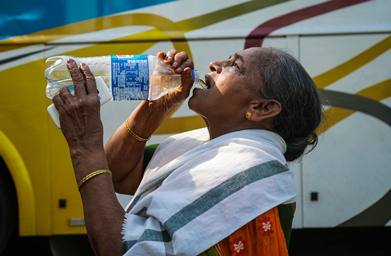 A woman is drinking water from water bottles on a hot summer day in Kolkata, India on 13 April 2023.