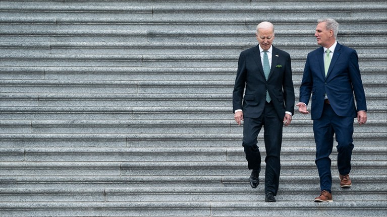 President Joe Biden walks down a flight of stairs beside House Speaker Kevin McCarthy.